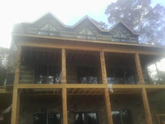 Dormers and porch framing on a large log home under construction — Roof Coating work by our crew in Uniontown